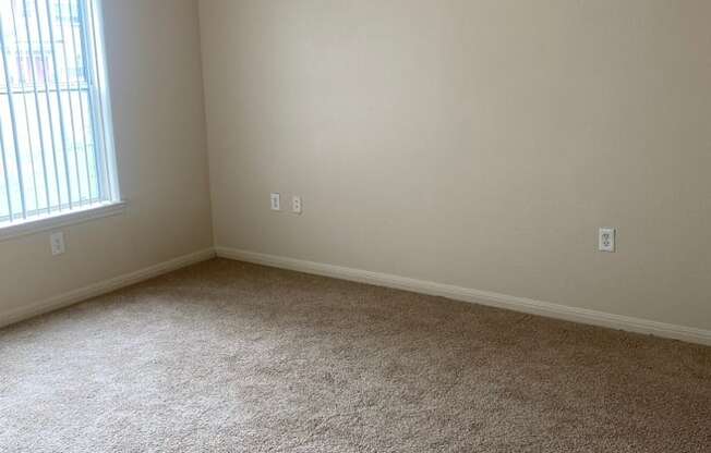 an empty room with a carpeted floor and a window