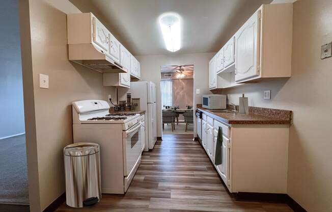 a kitchen with white appliances and white cabinets and a vinyl floor