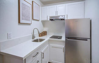 A kitchen with white cabinets and a stainless steel refrigerator.