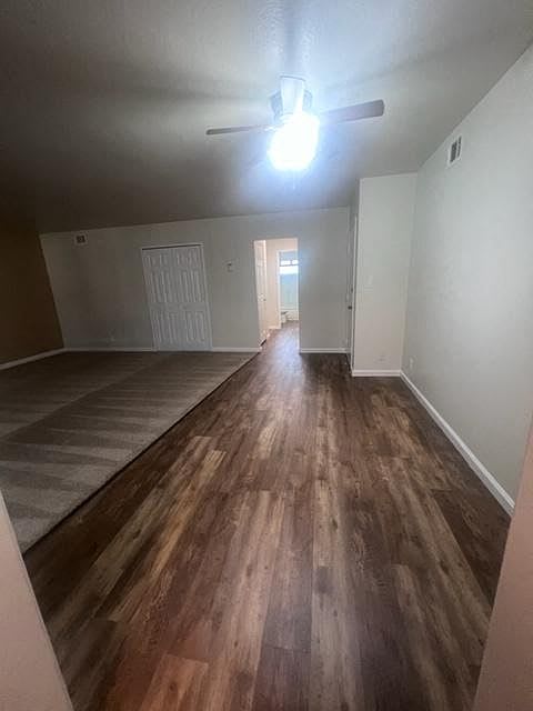 an empty living room with wood floors and a ceiling fan