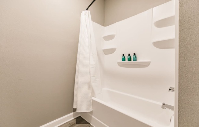 a bathroom with a tub and a shower and a white shower curtain