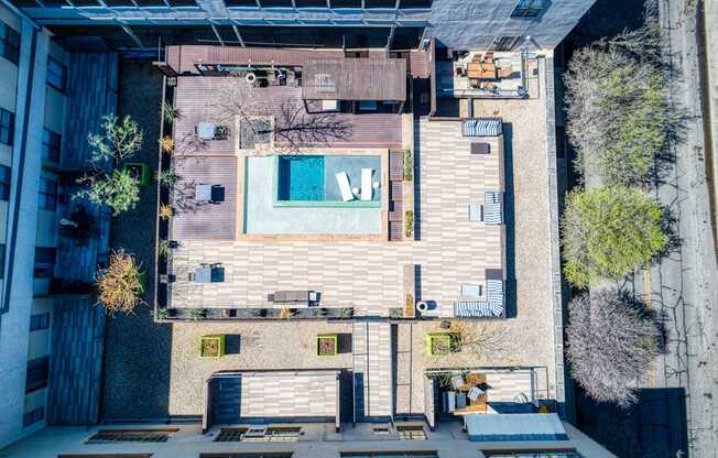 A pool is surrounded by a patio and a building.