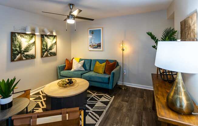a living room with a blue couch and yellow and orange pillows