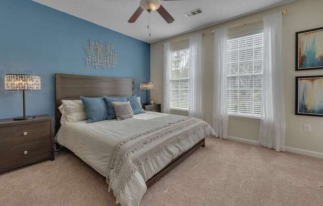 A bedroom with a bed, dresser, and ceiling fan.