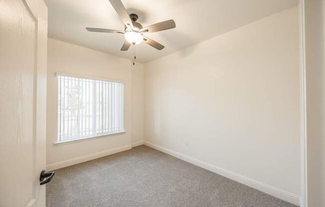 A room with a ceiling fan and carpeted floor.
