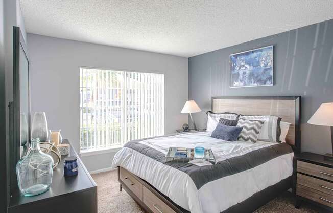 A bedroom with a large bed and a window with blinds.