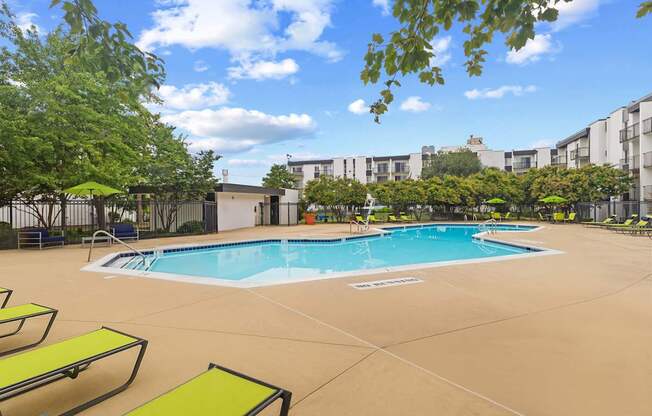 A large outdoor swimming pool surrounded by sun loungers and trees.