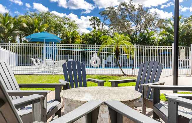 A patio with chairs and a table overlooking a pool.