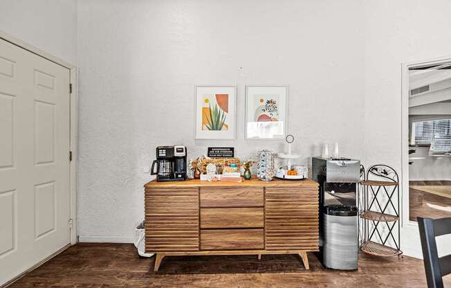 A white wall with a wooden cabinet and a fridge in the corner.