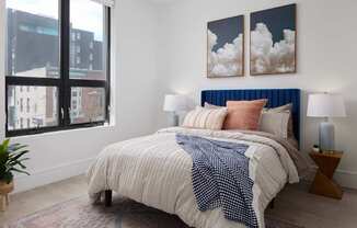 A bedroom with a large bed and two paintings on the wall.