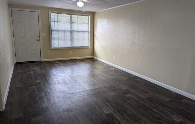 an empty living room with wood floors and a window