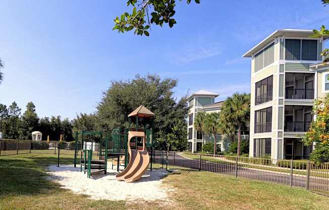 A playground with a slide and a building in the background.