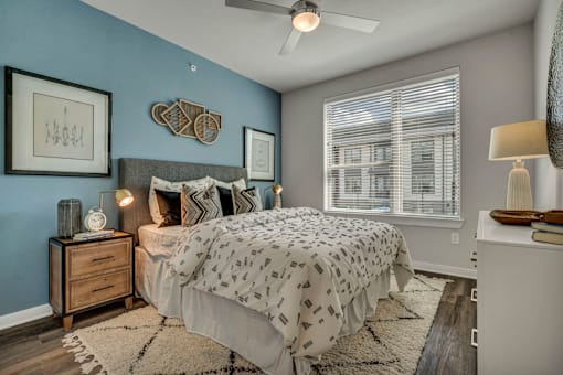 A bedroom with a bed, nightstand, and a ceiling fan.
