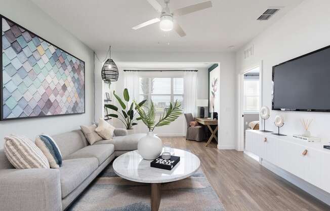 a living room and solarium with ceiling fan, wood-style floors, and model decor