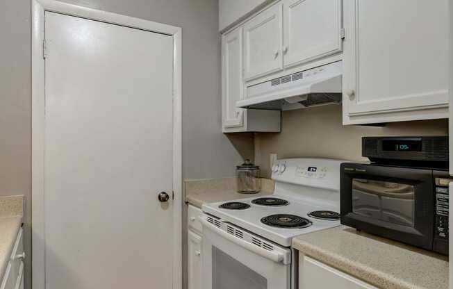 a kitchen with white cabinets and appliances and a white door