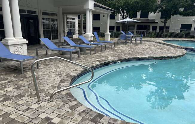 a resort style pool with blue chairs and a building in the background