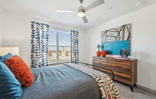 A bedroom with a bed, a dresser, and a painting on the wall.