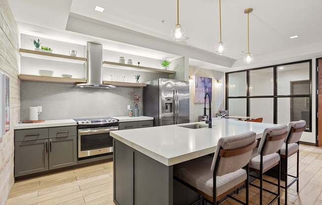 A modern kitchen with a large island and grey cabinets.