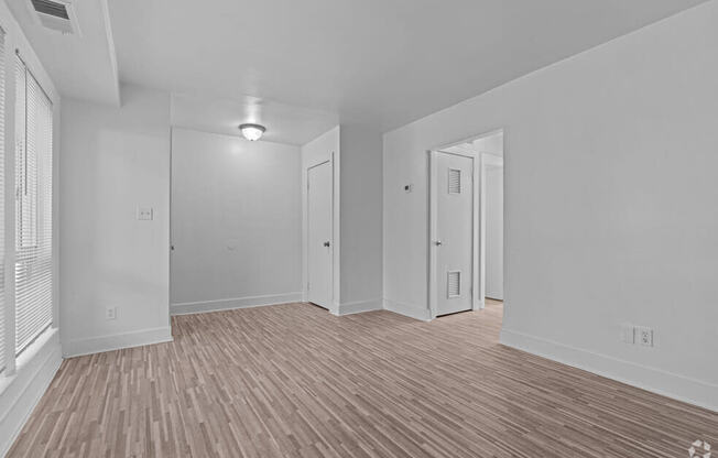 the living room and dining room of an empty house with wood flooring