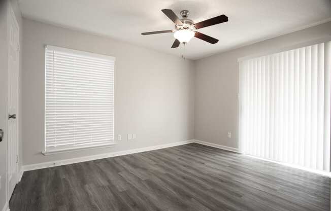 an empty living room with wood floors and a ceiling fan