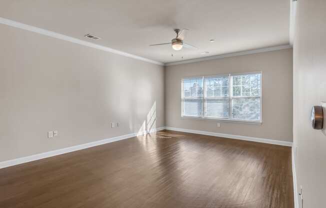 an empty living room with wood floors and a ceiling fan