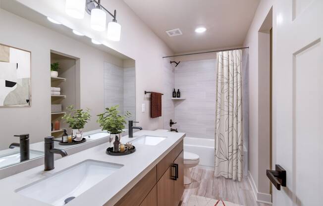 Pet-Friendly Apartments In Raymore, MO - Bathroom With Designer LVT Floors, Large Garden Soaking Shower, Large Mirror, Custom Vanity Cabinets, And Upgraded Plumbing Fixtures.