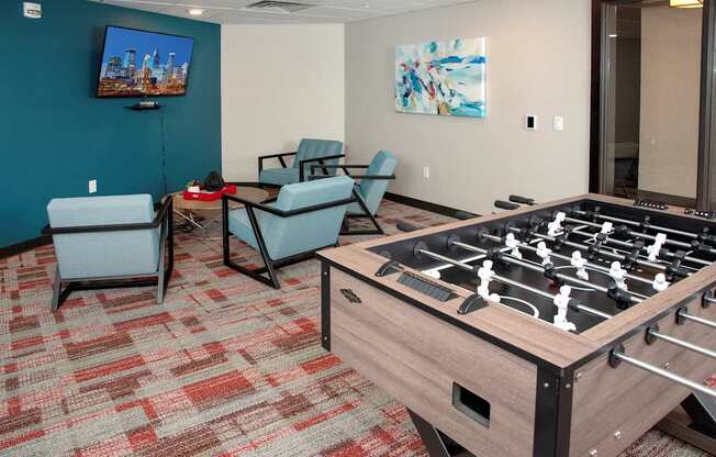 A foosball table is in the middle of a room with two chairs and a television.
