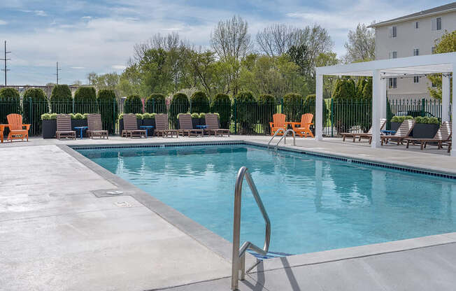 A pool with a metal ladder and chairs around it.