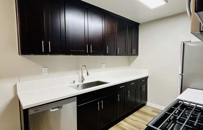 a kitchen with black cabinets and a white counter top and a stove and refrigerator