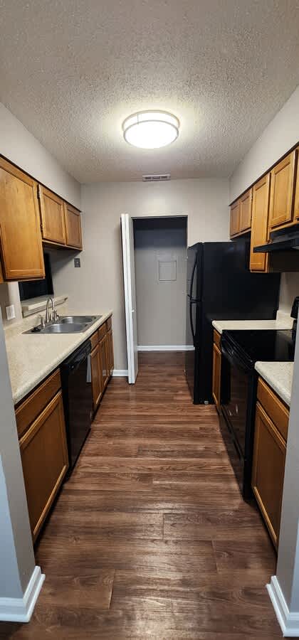 A kitchen with wooden cabinets and a black fridge.