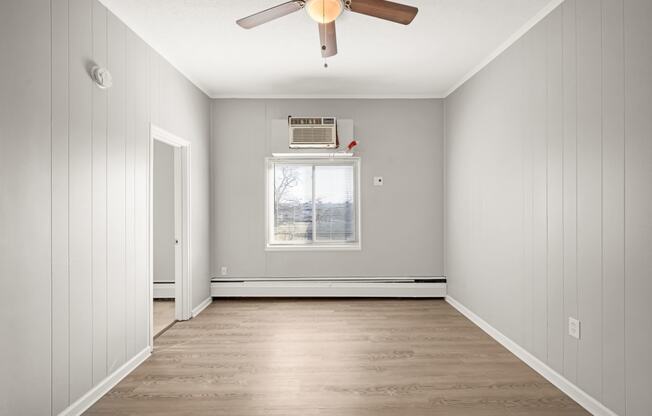 an empty room with a ceiling fan and a window