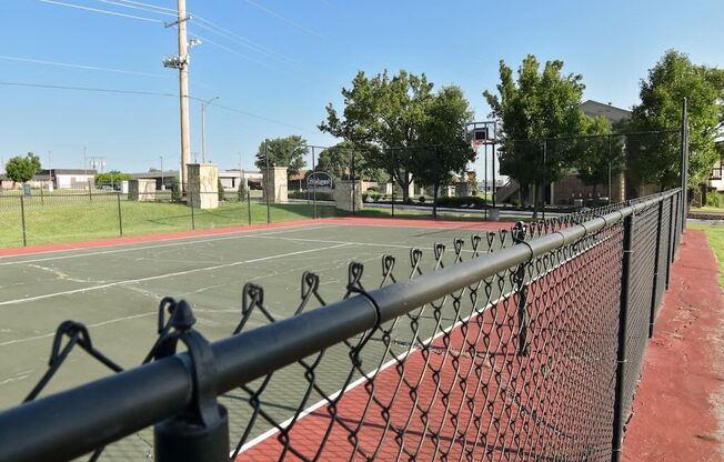 a tennis court with a fence and trees