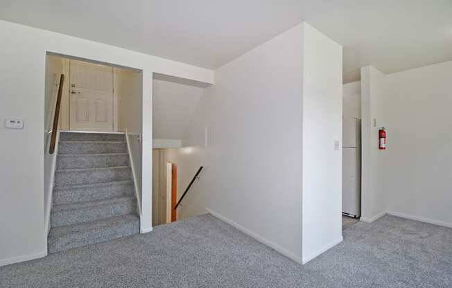 a renovated living room with a carpeted staircase and white walls