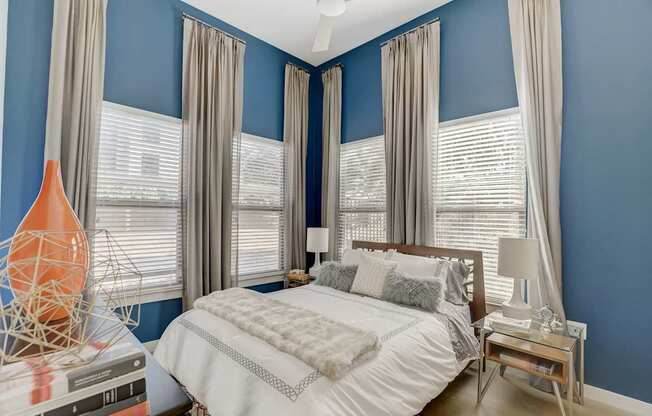A bedroom with a bed, nightstand, and a vase on the side table at Infinity on the Point Apartments, Texas