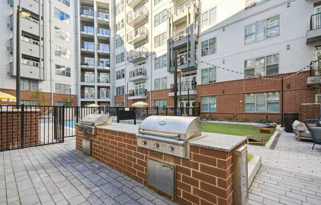 a barbecue grill on a brick wall in front of an apartment building at Link Apartments® Calyx, North Carolina, 27517