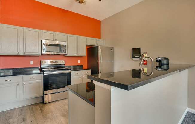 community kitchen with orange wall and stainless steel appliances