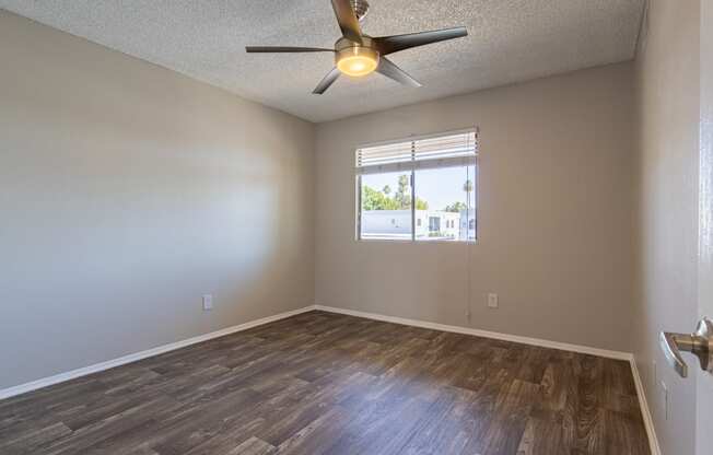 an empty bedroom with a ceiling fan and a window