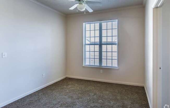 A room with a ceiling fan and a window with blinds.