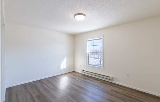 a bedroom with white walls and a window. Fargo, ND Stonebridge Apartments