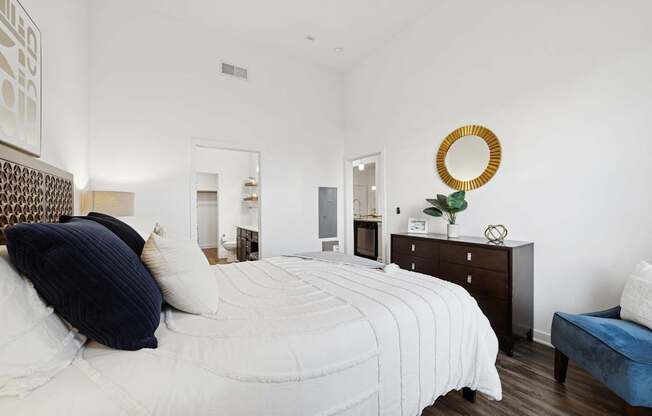 A bedroom with a large bed and a mirror on the wall.