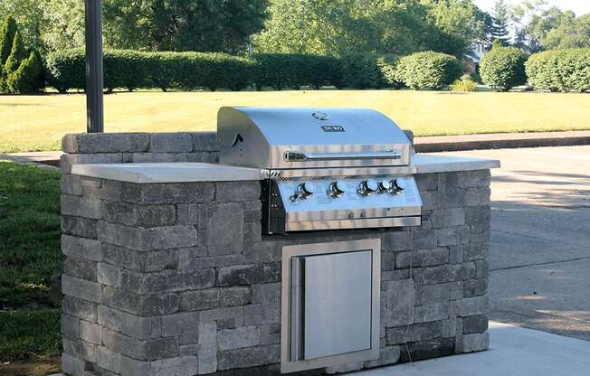 a stone outdoor kitchen with a grill in a park