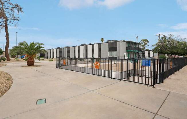 A black fence surrounds a concrete area with a building in the background.