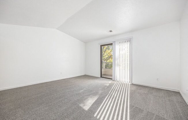 an empty living room with a cathedral ceiling and carpeting at Hampton Lakes Apartments, Michigan, 49534