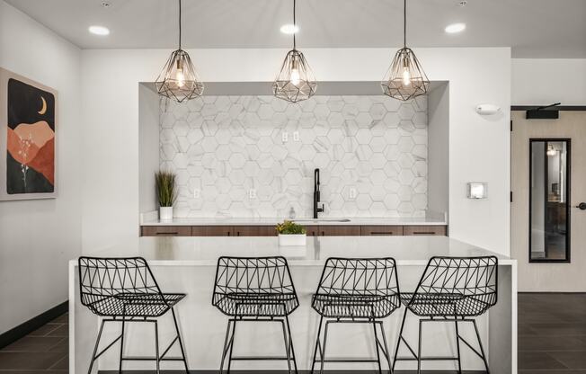 a kitchen with four bar stools in front of a white counter and a wall