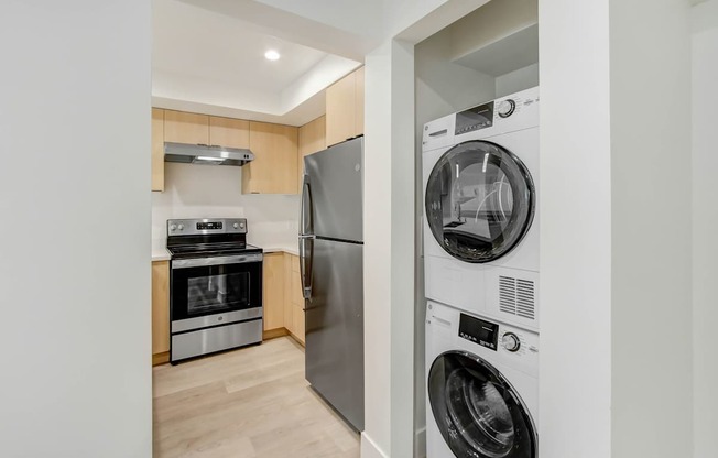 A modern kitchen with a washing machine and dryer stacked on top of each other.