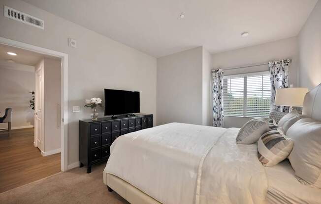 A bedroom with a large bed and a TV on a dresser.