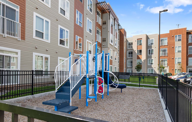 a blue playground in front of an apartment building