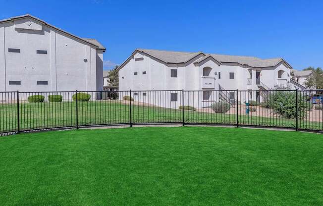 A white building with a black fence and green grass in front.