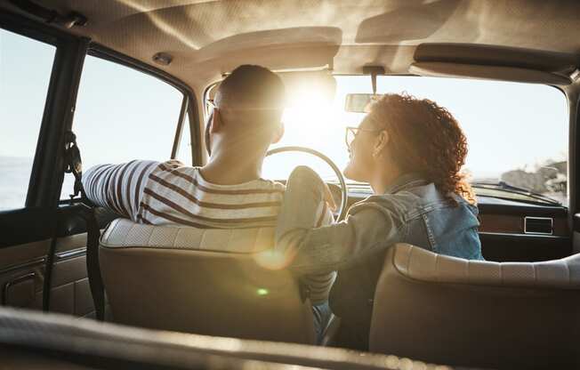 a man and woman sitting in a car looking out of the window at North Grove, Riverside  