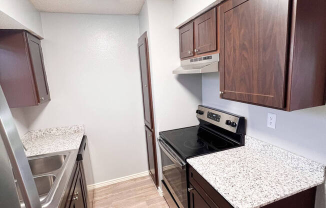 a kitchen with granite countertops and stainless steel appliances and wooden cabinets